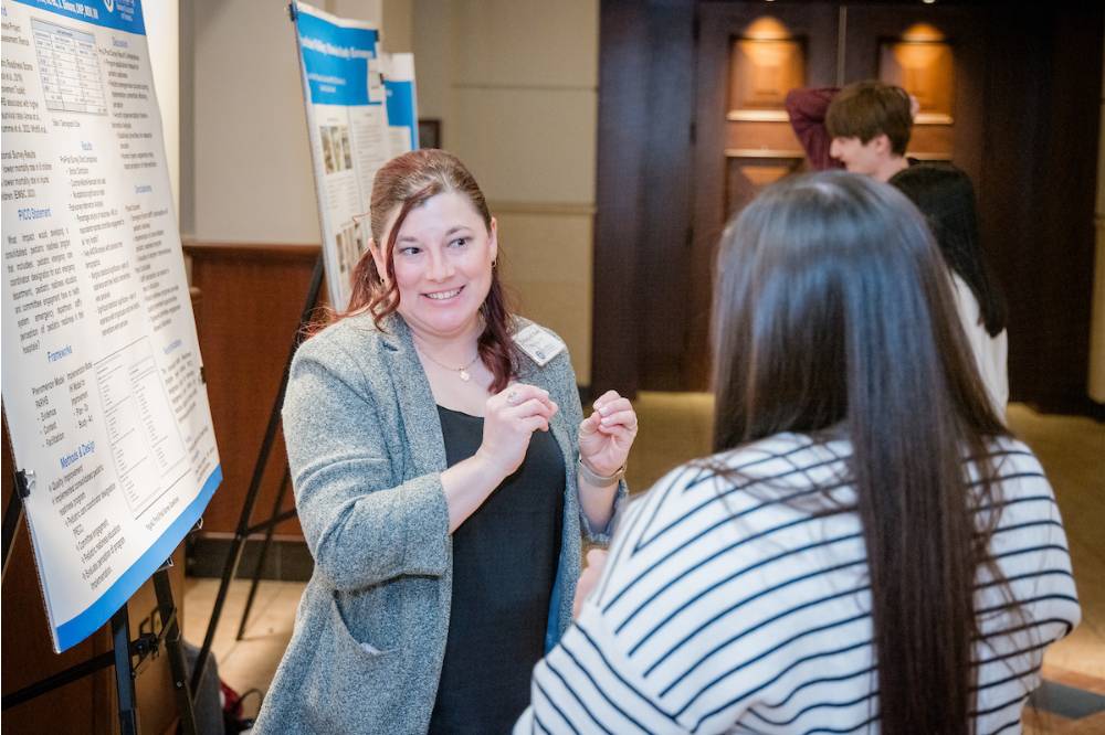 Rebekah Sabo (left) explaining her research